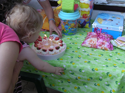 Blowing out her two birthday candles, presents waiting nearby